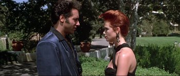 Movie still from “The Adventures of Ford Fairlane” (1990), directed by Renny Harlin – A man and a woman standing next to each other in a park; Medium shot, Over the shoulder angle