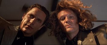 Movie still from “The Adventures of Ford Fairlane” (1990), directed by Renny Harlin – Two men are posing for a picture together; Close Up shot, Low angle