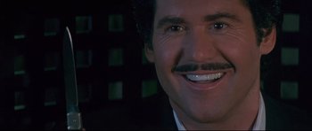 Movie still from “The Adventures of Ford Fairlane” (1990), directed by Renny Harlin – Close up of a man with a mustache smiling for the camera; Close Up shot, Low angle