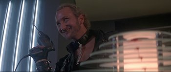 Movie still from “The Adventures of Ford Fairlane” (1990), directed by Renny Harlin – A man in a black leather jacket and a collar; Close Up shot, Low angle