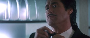 Movie still from “The Adventures of Ford Fairlane” (1990), directed by Renny Harlin – A person tying a tie; Close Up shot, Low angle