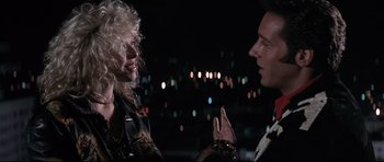Movie still from “The Adventures of Ford Fairlane” (1990), directed by Renny Harlin – A man and a woman talking to each other in front of lights; Close Up shot, Over the shoulder angle