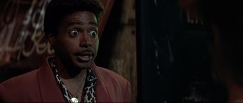 Movie still from “The Adventures of Ford Fairlane” (1990), directed by Renny Harlin – A person wearing a suit and tie; Close Up shot, Low angle