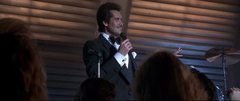 Movie still from “The Adventures of Ford Fairlane” (1990), directed by Renny Harlin – A man in a tuxedo is holding a microphone; Medium shot, Low angle