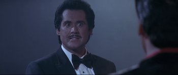 Movie still from “The Adventures of Ford Fairlane” (1990), directed by Renny Harlin – A person wearing a suit and tie; Close Up shot, Low angle