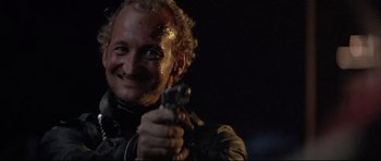 Movie still from “The Adventures of Ford Fairlane” (1990), directed by Renny Harlin – A man holding a gun in his right hand; Close Up shot, Low angle