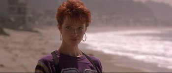 Movie still from “The Adventures of Ford Fairlane” (1990), directed by Renny Harlin – A woman with red hair standing on the beach; Close Up shot, Low angle