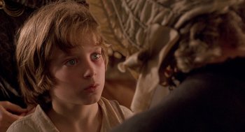 Movie still from “The Adventures of Huck Finn” (1993), directed by Stephen Sommers – A young boy with blue eyes stares into the distance; Close Up shot, Over the shoulder angle