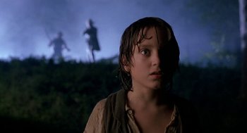 Movie still from “The Adventures of Huck Finn” (1993), directed by Stephen Sommers – A young boy standing in the rain looking at the camera; Close Up shot, Over the shoulder angle