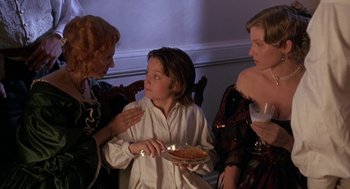 Movie still from “The Adventures of Huck Finn” (1993), directed by Stephen Sommers – Two women and a boy are eating pizza together; Medium shot, High angle