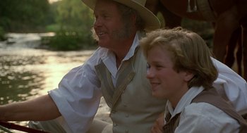 Movie still from “The Adventures of Huck Finn” (1993), directed by Stephen Sommers – A man sitting next to a young boy wearing a hat; Close Up shot, Over the shoulder angle