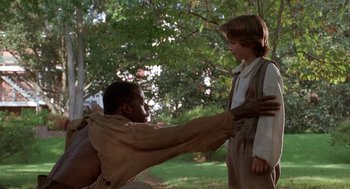 Movie still from “The Adventures of Huck Finn” (1993), directed by Stephen Sommers – A young boy is holding the hand of an older man; Medium shot, Over the shoulder angle
