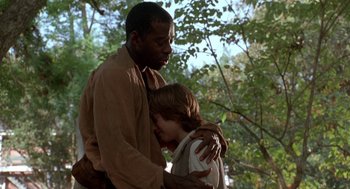 Movie still from “The Adventures of Huck Finn” (1993), directed by Stephen Sommers – A man and a boy are hugging in a forest; Medium shot, Over the shoulder angle