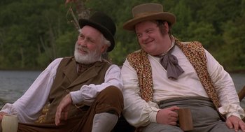 Movie still from “The Adventures of Huck Finn” (1993), directed by Stephen Sommers – A couple of men sitting next to each other on top of a bench; Medium shot, Low angle