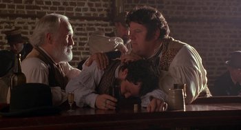 Movie still from “The Adventures of Huck Finn” (1993), directed by Stephen Sommers – A group of people sitting around a table; Medium shot, Over the shoulder angle
