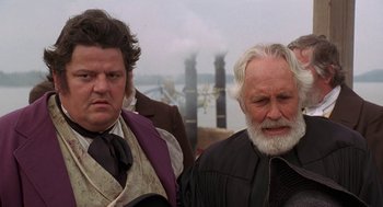 Movie still from “The Adventures of Huck Finn” (1993), directed by Stephen Sommers – Two men standing next to each other near a body of water; Close Up shot, Over the shoulder angle