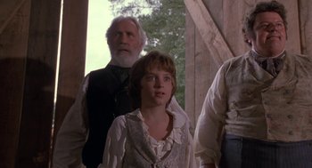Movie still from “The Adventures of Huck Finn” (1993), directed by Stephen Sommers – A man and a woman standing next to each other in front of an older man; Medium shot, Low angle