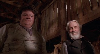 Movie still from “The Adventures of Huck Finn” (1993), directed by Stephen Sommers – A man and a woman standing next to each other in a barn; Medium shot, Low angle