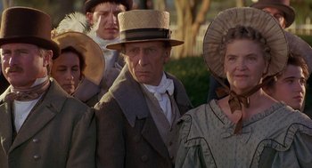 Movie still from “The Adventures of Huck Finn” (1993), directed by Stephen Sommers – An older man and two women wearing hats; Medium shot, Low angle