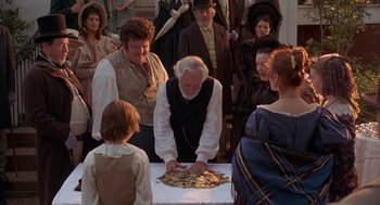 Movie still from “The Adventures of Huck Finn” (1993), directed by Stephen Sommers – An older man cutting a cake with a knife; Medium shot, High angle
