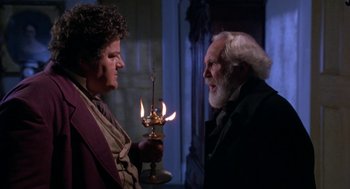 Movie still from “The Adventures of Huck Finn” (1993), directed by Stephen Sommers – Two men standing next to each other holding a lit candle; Medium shot, Over the shoulder angle