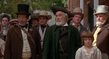 Movie still from “The Adventures of Huck Finn” (1993), directed by Stephen Sommers – A group of men in hats and coats standing next to each other; Medium shot, Low angle