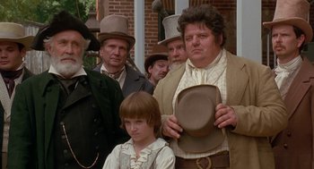 Movie still from “The Adventures of Huck Finn” (1993), directed by Stephen Sommers – A group of people standing next to each other wearing hats; Medium shot, Low angle