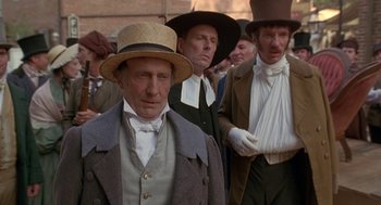 Movie still from “The Adventures of Huck Finn” (1993), directed by Stephen Sommers – A group of men standing next to each other wearing hats; Medium shot, Over the shoulder angle