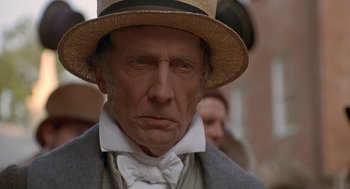 Movie still from “The Adventures of Huck Finn” (1993), directed by Stephen Sommers – An older man wearing a hat and a bow tie; Close Up shot, Low angle