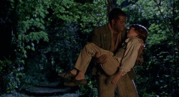 Movie still from “The Adventures of Huck Finn” (1993), directed by Stephen Sommers – A man carrying a woman in a forest; Medium shot, High angle