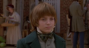 Movie still from “The Adventures of Huck Finn” (1993), directed by Stephen Sommers – A young boy wearing a green jacket and bow tie; Close Up shot, Over the shoulder angle