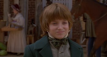 Movie still from “The Adventures of Huck Finn” (1993), directed by Stephen Sommers – A young boy wearing a green jacket and a bow tie; Close Up shot, Over the shoulder angle