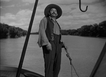 Movie still from “The Adventures of Mark Twain” (1944), directed by Irving Rapper – A man standing next to a boat on a river; Medium shot, Low angle