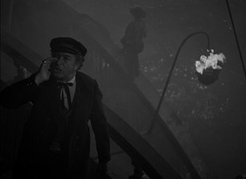 Movie still from “The Adventures of Mark Twain” (1944), directed by Irving Rapper – A black and white photo of a man smoking a cigarette; Medium shot, High angle