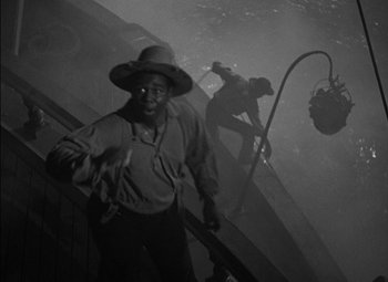 Movie still from “The Adventures of Mark Twain” (1944), directed by Irving Rapper – A man with a hat on standing next to an escalator; Medium shot, High angle