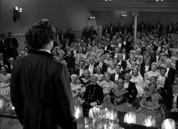 Movie still from “The Adventures of Mark Twain” (1944), directed by Irving Rapper – A woman standing in front of a crowd of people in front of candles; Wide shot, High angle