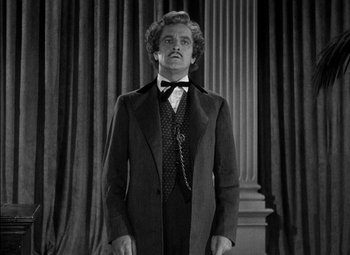 Movie still from “The Adventures of Mark Twain” (1944), directed by Irving Rapper – A black and white photo of a man in a suit and tie; Medium shot, Low angle