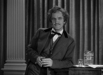 Movie still from “The Adventures of Mark Twain” (1944), directed by Irving Rapper – A black and white photo of a man sitting at a table; Medium shot, Low angle