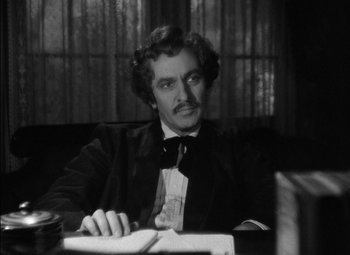 Movie still from “The Adventures of Mark Twain” (1944), directed by Irving Rapper – A black and white photo of a man sitting at a table; Close Up shot, Over the shoulder angle