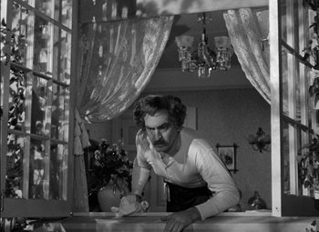 Movie still from “The Adventures of Mark Twain” (1944), directed by Irving Rapper – A black and white photo of a man leaning on a wall; Medium shot, Low angle