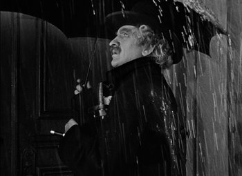 Movie still from “The Adventures of Mark Twain” (1944), directed by Irving Rapper – A black and white photo of a man holding an umbrella; Medium shot, Low angle