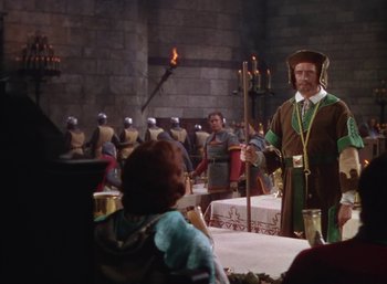 Movie still from “The Adventures of Robin Hood” (1938), directed by William Keighley – A man dressed in medieval clothing stands in front of a group of people; Medium shot, Over the shoulder angle