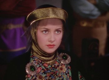 Movie still from “The Adventures of Robin Hood” (1938), directed by William Keighley – A woman wearing a gold headpiece and a floral dress; Close Up shot, Over the shoulder angle