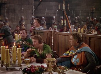 Movie still from “The Adventures of Robin Hood” (1938), directed by William Keighley – A group of people sitting at a table with candles; Wide shot, High angle