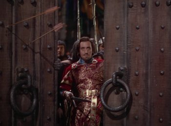 Movie still from “The Adventures of Robin Hood” (1938), directed by William Keighley – A group of men in medieval garb standing next to a door; Medium shot, Over the shoulder angle