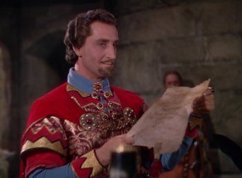 Movie still from “The Adventures of Robin Hood” (1938), directed by William Keighley – A man in a red and gold outfit holding a piece of parchment paper; Medium shot, High angle