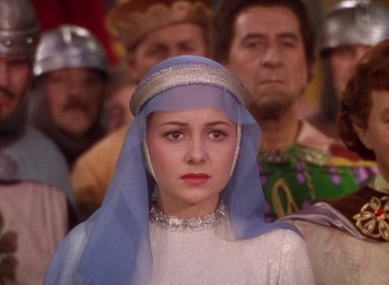 Movie still from “The Adventures of Robin Hood” (1938), directed by William Keighley – A woman with a blue head covering in front of a group of people; Close Up shot, Over the shoulder angle