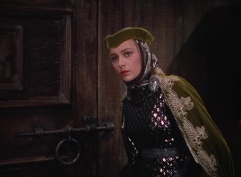Movie still from “The Adventures of Robin Hood” (1938), directed by William Keighley – A woman in a medieval outfit standing in front of a door; Medium shot, Low angle