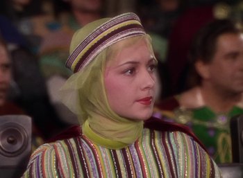 Movie still from “The Adventures of Robin Hood” (1938), directed by William Keighley – A woman wearing a colorful outfit with a veil on top of her head; Close Up shot, Over the shoulder angle