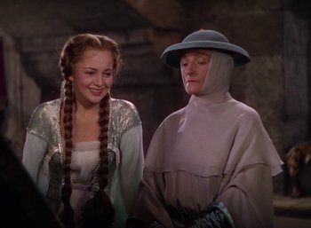 Movie still from “The Adventures of Robin Hood” (1938), directed by William Keighley – Two women dressed in medieval clothing standing next to each other; Medium shot, Over the shoulder angle
